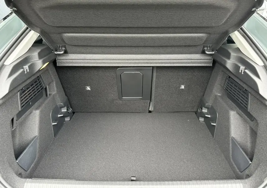 Coffre ouvert vu de l’arrière d’une Citroën C4 Manhattan Green avec intérieur noir et compartiments latéraux.