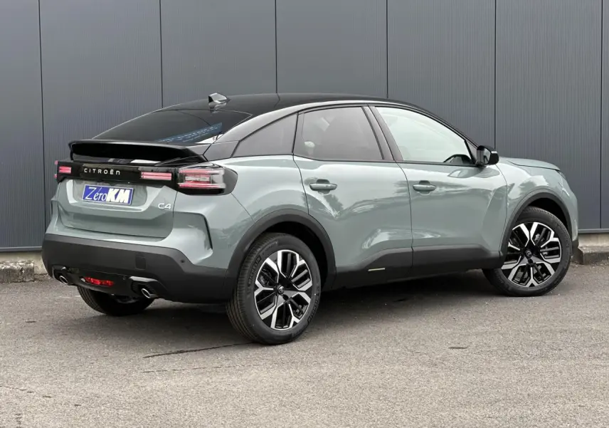 Vue 3/4 arrière droite de la Citroën C4 2025 Manhattan Green avec toit noir et jantes alliage 18 pouces.