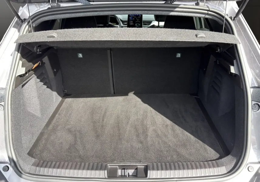 Coffre ouvert vu de l'arrière d'une Renault Symbioz gris clair, montrant un espace de chargement propre et spacieux.