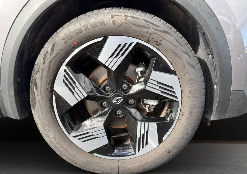 Gros plan sur la roue avant droite du Renault Symbioz gris clair, mettant en valeur la jante noire et argentée au design géométrique.