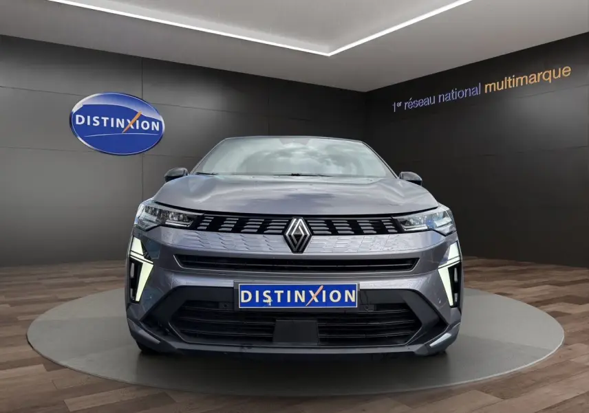 Vue avant d'une Renault Symbioz gris clair avec éclairage LED distinctif, présentée en showroom Distinxion.