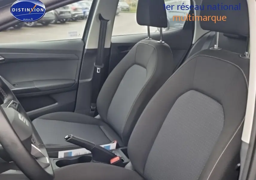 Vue intérieure côté conducteur de la SEAT Ibiza gris 2025, sièges tissu gris et volant multifonction cuir.