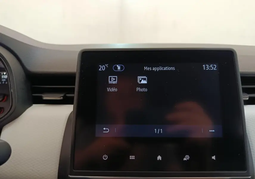 Écran tactile central affichant les applications vidéo et photo, intérieur de Renault Clio blanc, vue frontale rapprochée.