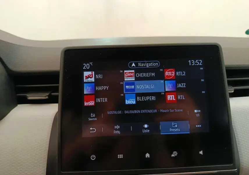Écran tactile central de la Renault Clio blanc 2023 affichant les stations radio et la navigation.