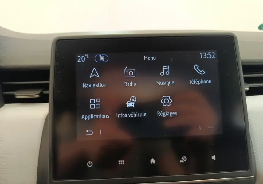 Écran tactile central de la Renault Clio blanc, affichant le menu principal avec navigation et musique.