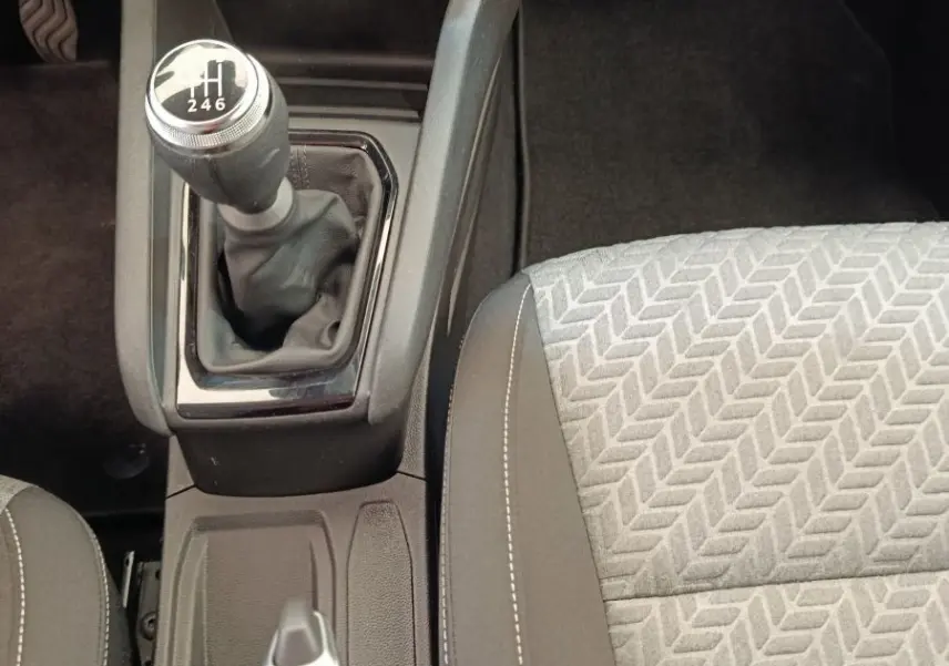 Vue rapprochée de la console centrale d'une Renault Clio blanche 2023, avec levier de vitesse manuel et siège tissu gris.