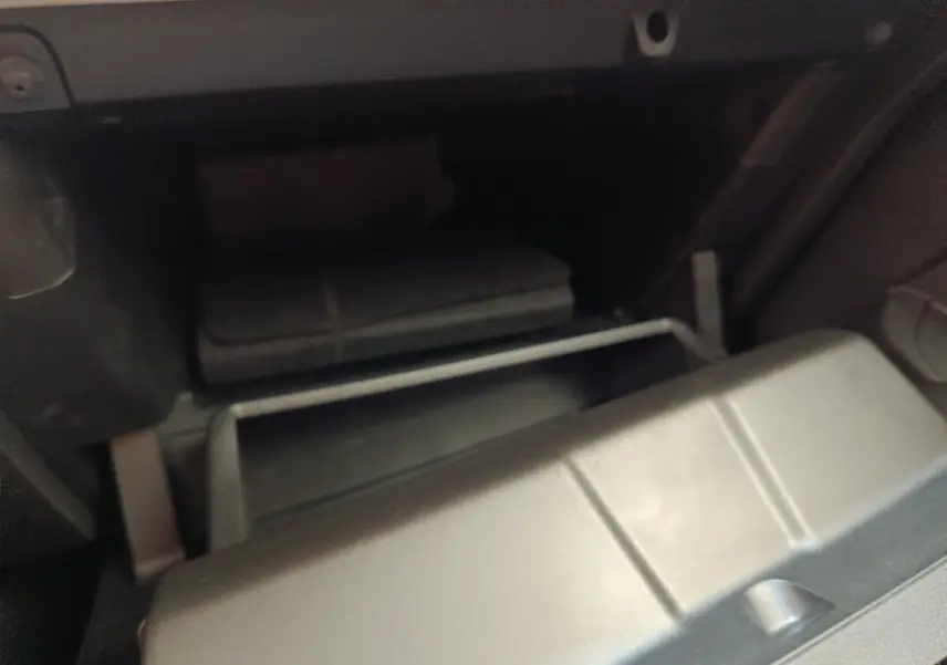 Gant de boîte à gants ouvert en plastique gris à l'intérieur d'une Renault Clio blanche, vue intérieure côté passager.