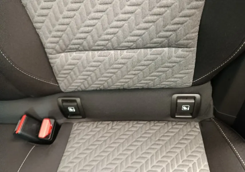 Détail de la banquette arrière grise avec fixation Isofix et boucle de ceinture rouge dans une Renault Clio blanche.