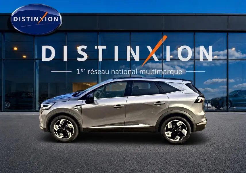 Profil droit d’un Renault Symbioz gris cassiopée avec jantes alu, stationné devant une vitrine Distinxion.