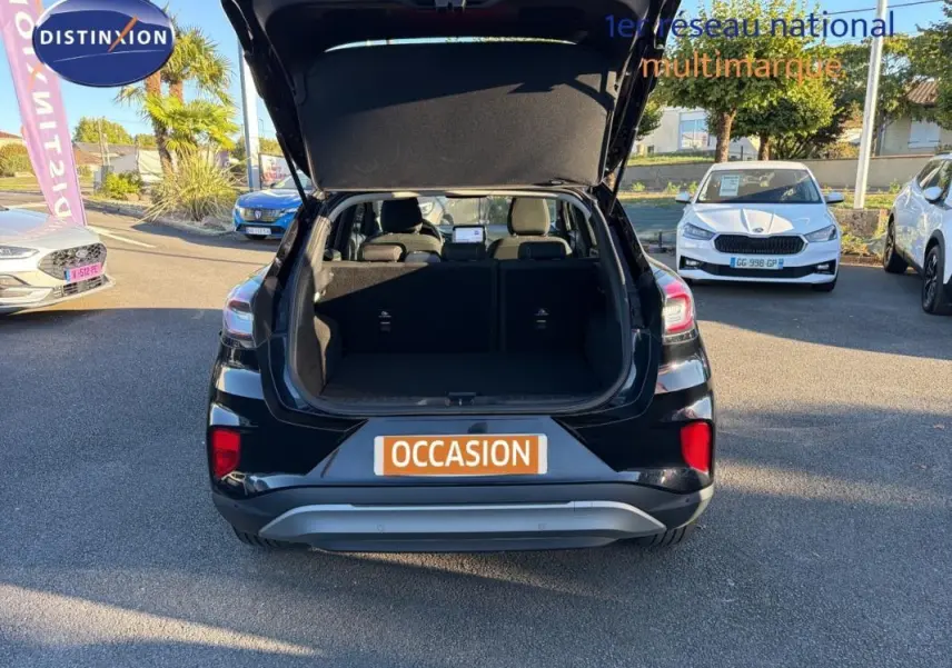 Vue arrière d’un Ford Puma noir 2023 avec coffre ouvert sur un parking en plein jour.