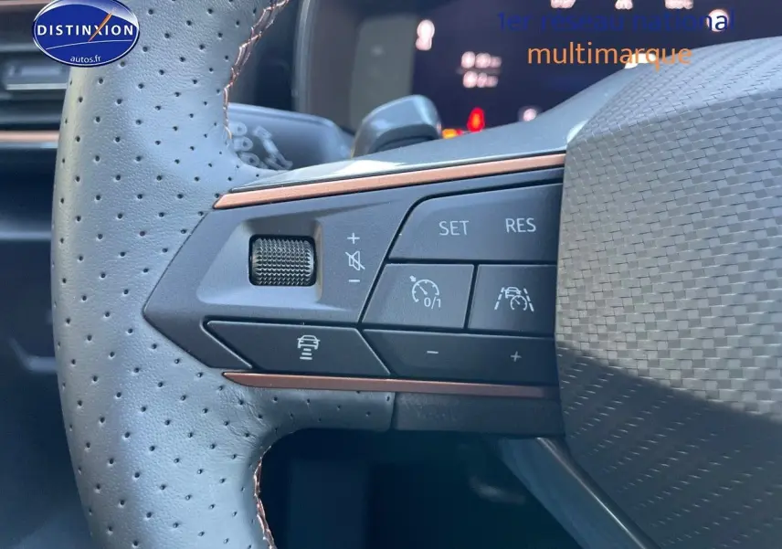 Gros plan sur les commandes du volant en cuir perforé gris d'une CUPRA Formentor 1.4 E-HYBRID 2024, avec boutons de régulateur.