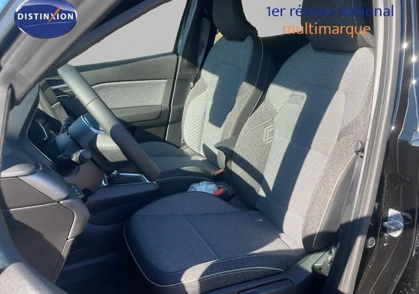 Vue intérieure côté conducteur du Renault Captur E-Tech hybride 2025 avec sièges tissu noir et gris et volant visible.
