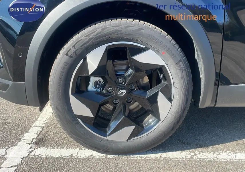 Gros plan sur la roue avant gauche du Renault Captur noir étoile métal, mettant en valeur la jante noire et argentée au design étoilé.
