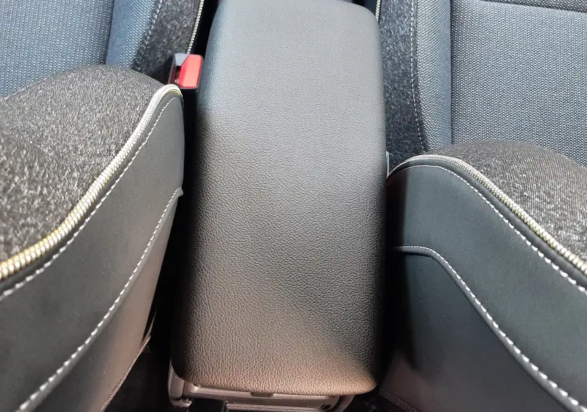 Vue rapprochée de l'accoudoir central en cuir noir entre les sièges avant en tissu gris du Renault Captur 2025.