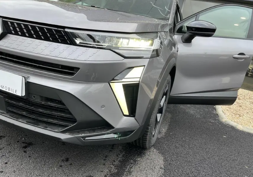 Vue avant droite du Renault Captur gris Cassiopée 2025 avec porte ouverte et éclairage LED allumé.
