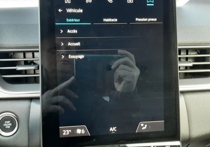 Écran tactile central du tableau de bord du Renault Captur 2025, affichant le menu véhicule avec commandes climatisation en dessous.