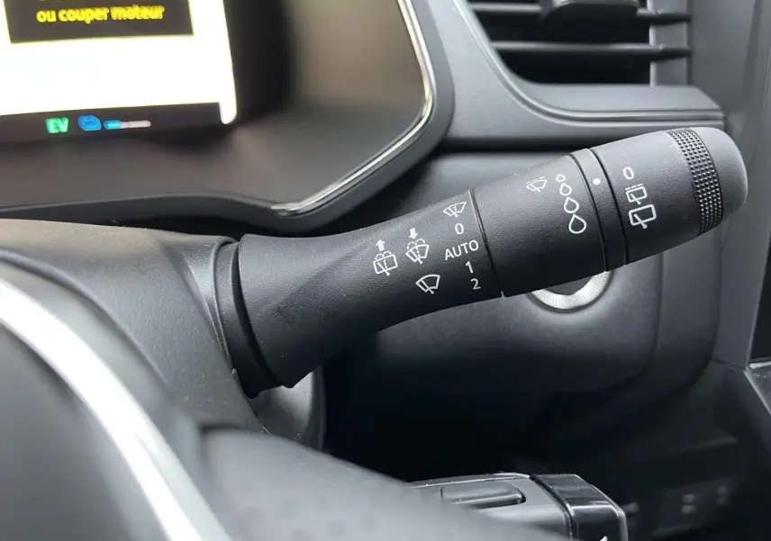 Gros plan sur la commande d’essuie-glace à droite du volant dans l’habitacle sombre du Renault Captur gris Cassiopée 2025.