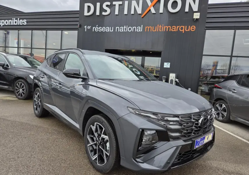 Hyundai Tucson 2025 gris métallisé en 3/4 avant, avec calandre N Line et jantes alliage 19 pouces visibles.