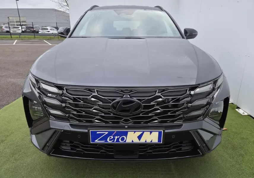 Vue avant centrée du Hyundai Tucson 2025 gris métallisé avec calandre noire N Line et feux LED distinctifs.