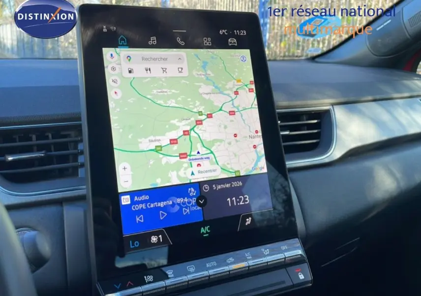 Vue rapprochée de l’écran tactile central du Renault Captur rouge désir métal avec toit noir, affichant la navigation GPS et la climatisation.