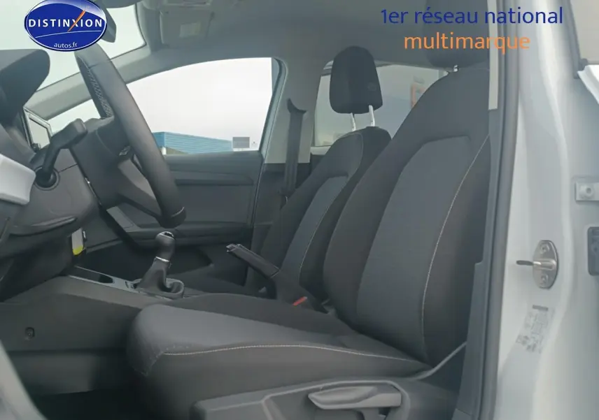 Vue intérieure côté conducteur de la SEAT Ibiza blanc Nevada 2025, sièges tissu gris et volant multifonction cuir.