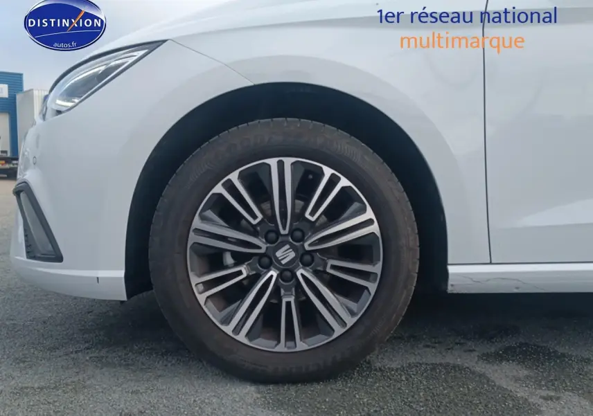 Gros plan sur la roue avant gauche et partie avant blanche d'une SEAT Ibiza 1.0 TSI 95 Copa avec jante design 16 pouces.