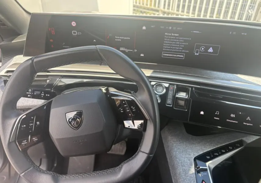 Vue intérieure du tableau de bord du Peugeot 3008 Hybrid 2025, avec volant compact et écran tactile panoramique.