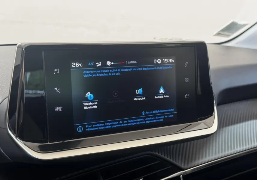 Écran tactile central de la Peugeot 208 jaune, vue rapprochée de la console avec affichage Bluetooth et Android Auto.