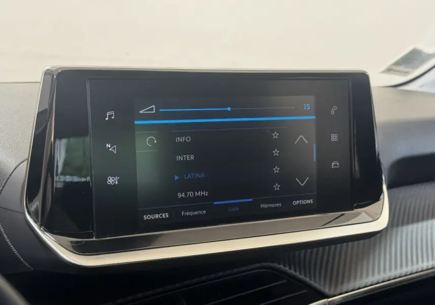 Écran tactile central 7 pouces de la Peugeot 208 jaune, vue rapprochée de l'interface multimédia affichant une radio FM.
