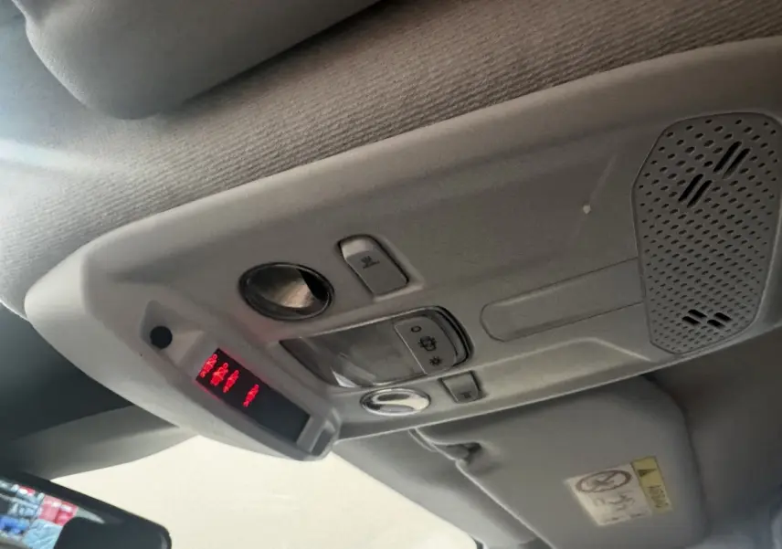 Vue intérieure en gros plan du plafonnier gris avec commandes et affichage lumineux rouge dans une Peugeot 208 jaune.