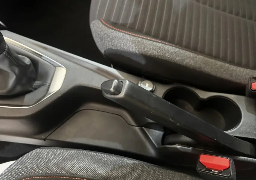Vue rapprochée de la console centrale de la Peugeot 208 2023, montrant le frein à main manuel et porte-gobelets noirs.