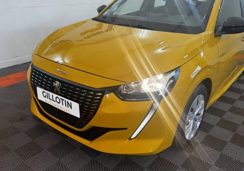 Vue 3/4 avant droite d'une Peugeot 208 jaune avec phares allumés et calandre noire distinctive.