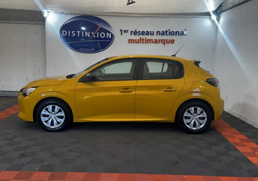 Profil droit d'une Peugeot 208 jaune 2023 garée en intérieur avec jantes alliage et vitres teintées.