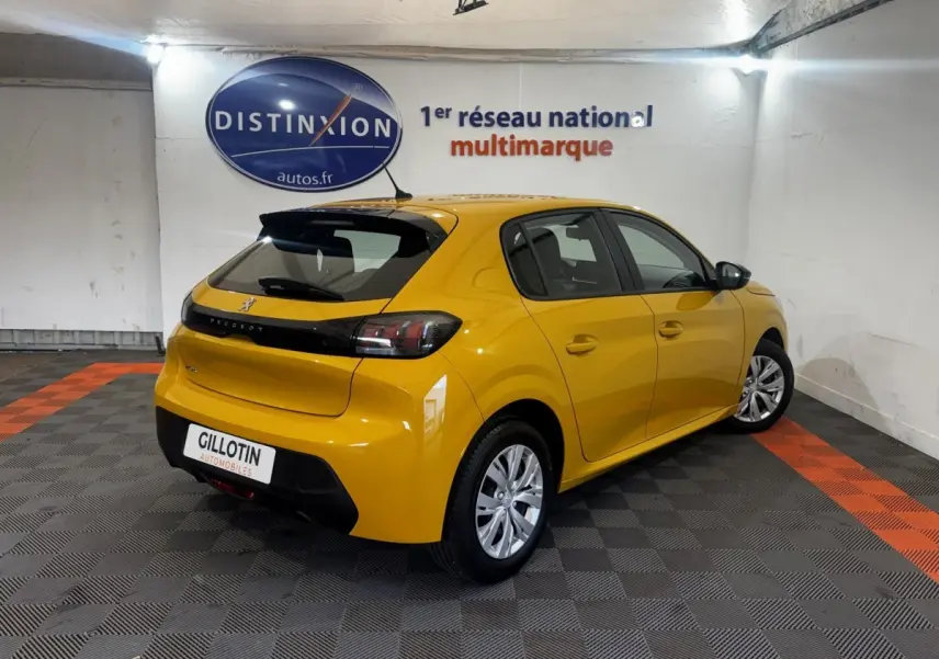 Vue 3/4 arrière droite d'une Peugeot 208 jaune vif stationnée en intérieur avec feux arrière sombres et jantes argentées.