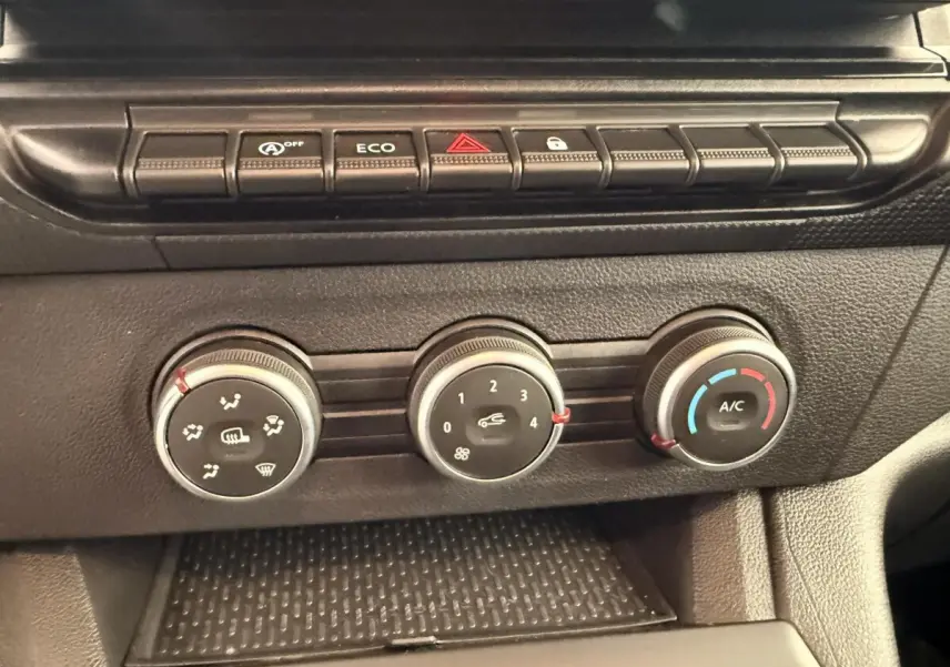 Gros plan sur les commandes de climatisation et boutons de fonction du tableau de bord du Renault Kangoo blanc 2023.