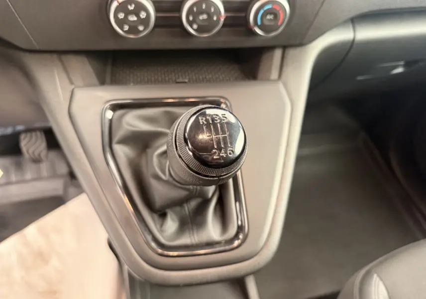 Gros plan sur le levier de vitesses manuel noir du Renault Kangoo GD Confort 2023, avec commandes de climatisation en arrière-plan.
