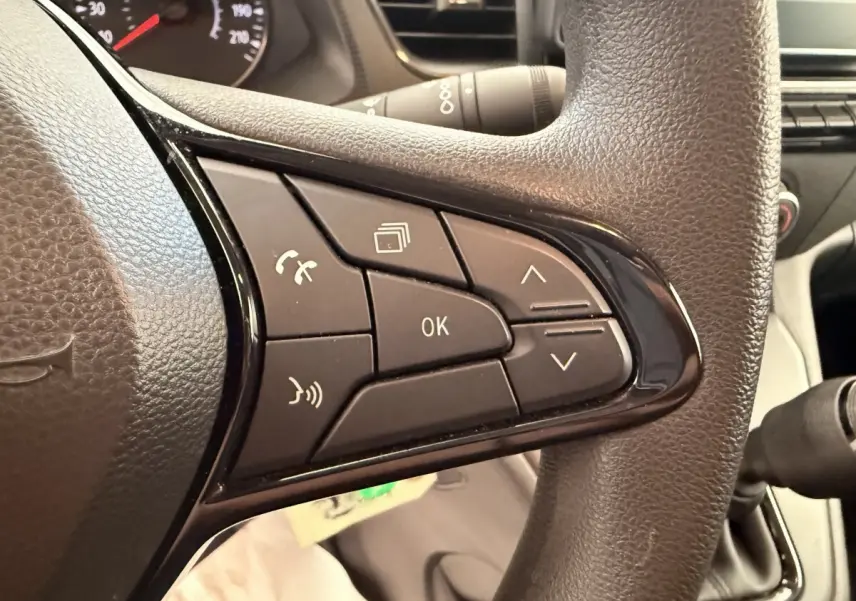 Gros plan sur les commandes multifonctions noires du volant du Renault Kangoo blanc, version GD Confort 2023.