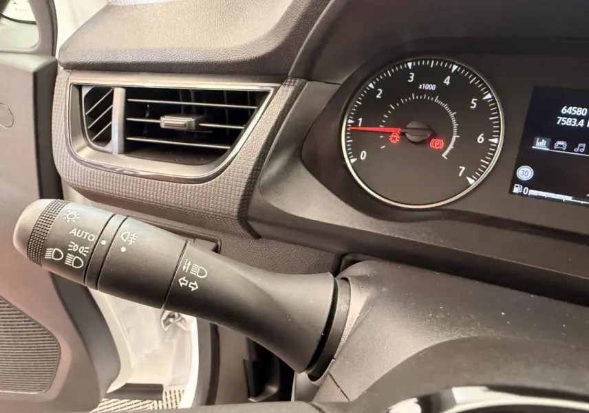 Gros plan sur la manette de phares et clignotants à gauche du tableau de bord noir du Renault Kangoo blanc 2023.