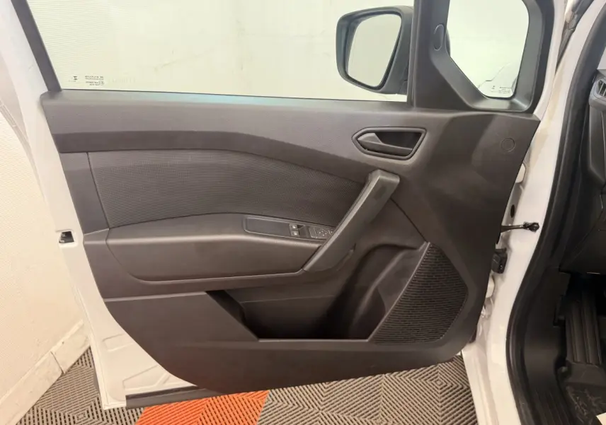 Vue intérieure de la porte avant gauche noire du Renault Kangoo blanc, avec commandes de vitres et rétroviseur visible.