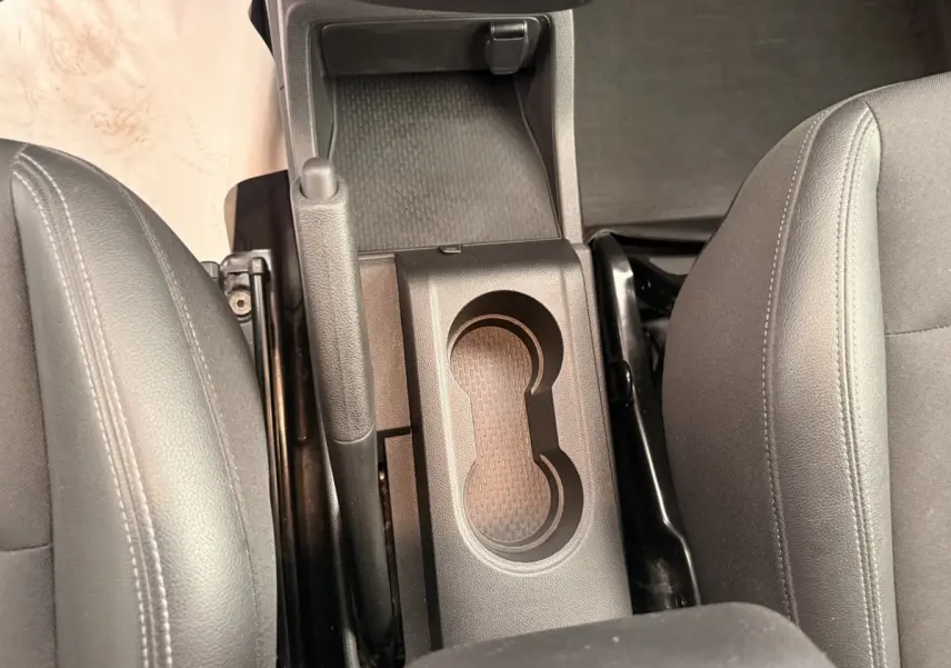 Vue plongeante sur la console centrale noire entre les sièges avant gris du Renault Kangoo blanc 2023.