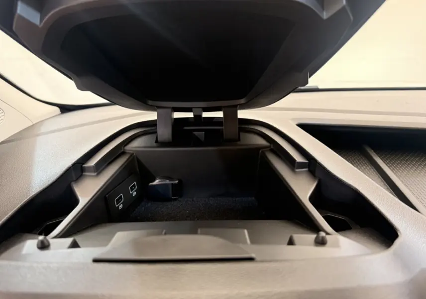 Vue rapprochée du compartiment de rangement ouvert sur le tableau de bord du Renault Kangoo blanc, avec ports USB visibles.
