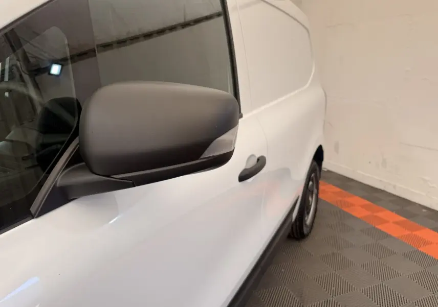 Vue latérale droite rapprochée du Renault Kangoo blanc, mettant en valeur le rétroviseur noir mat et la porte coulissante.
