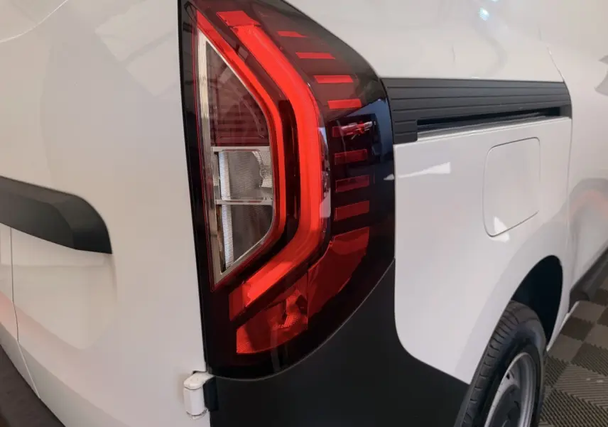 Gros plan sur le feu arrière droit rouge du Renault Kangoo blanc, avec la trappe à carburant visible sur le côté.