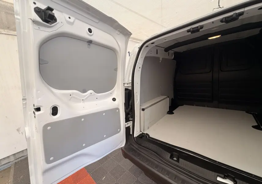 Vue arrière ouverte du Renault Kangoo blanc 2023 montrant l'espace de chargement vide avec cloison intérieure grise.