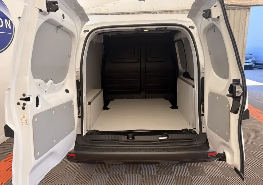 Vue arrière du Renault Kangoo blanc 2023 avec portes ouvertes montrant l'espace de chargement vide et cloison pleine noire.