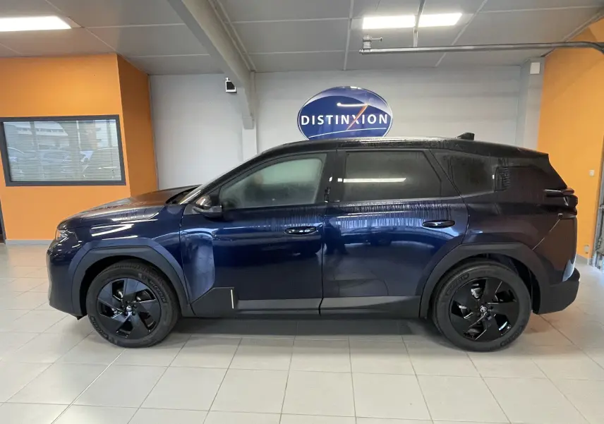 Profil côté gauche du Citroën C5 Aircross hybride 2026 bleu Eclipse avec toit noir et jantes noires en intérieur showroom.