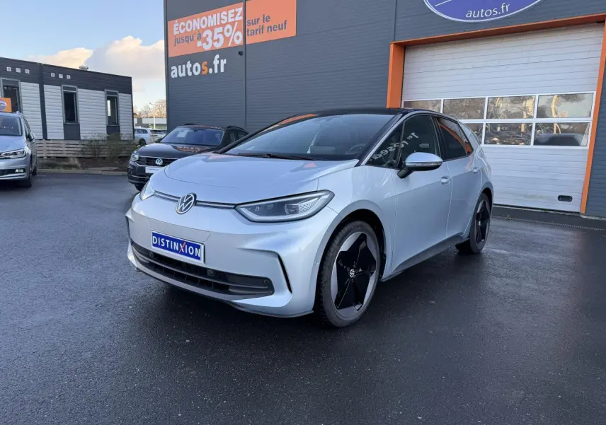 Vue 3/4 avant droite d'une Volkswagen ID.3 Pro S gris argent avec toit noir, stationnée devant un garage autos.fr