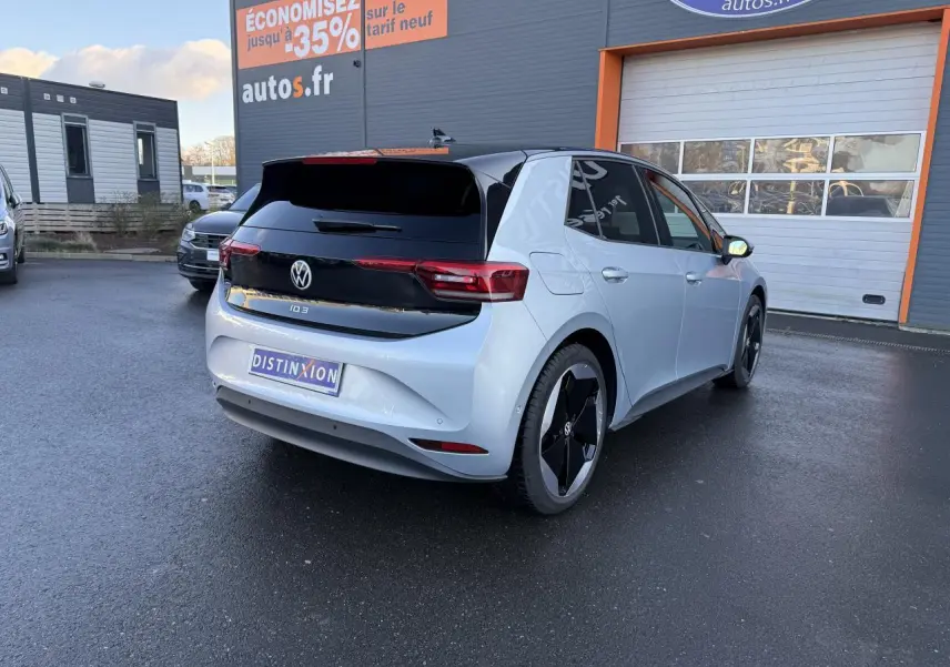 Vue 3/4 arrière droite d'une Volkswagen ID.3 Pro S gris argent avec toit noir et jantes noires au parking d'un concessionnaire.
