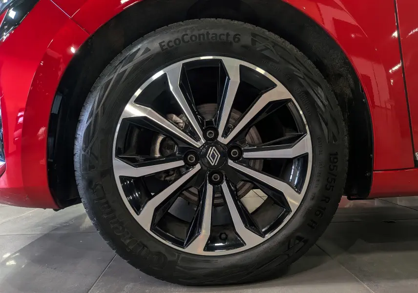 Gros plan sur la roue avant gauche de la Renault Clio V Rouge Flamme avec jante alliage bicolore et logo central Renault.