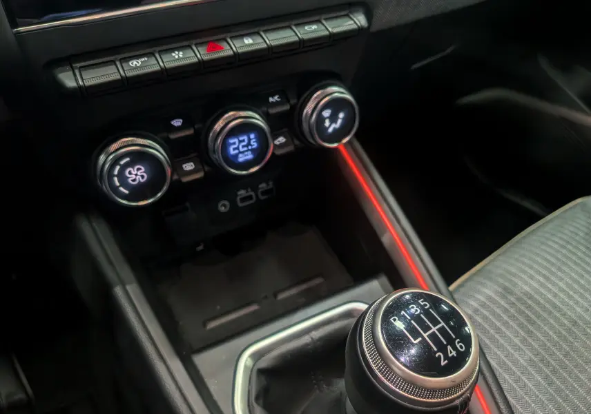 Gros plan sur la console centrale de la Renault Clio V, mettant en valeur la boîte manuelle et les commandes de climatisation.